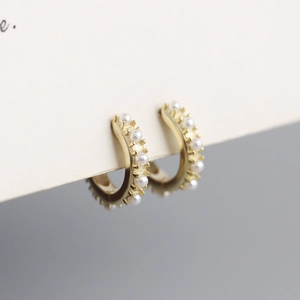 Close-up of gold hoop earrings with small pearls on white display card
