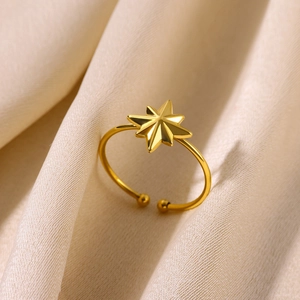 Macro shot of gold octagonal star open ring on champagne silk background