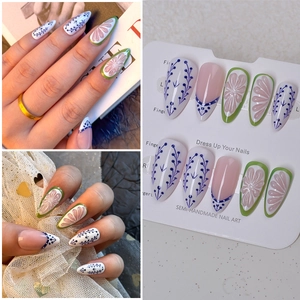 Detailed close-up of almond-shaped press-on nails with 3D floral carving and blue vine art