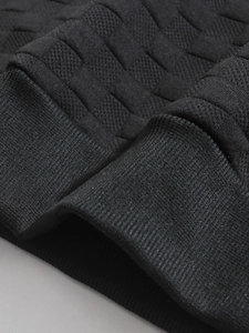 Macro shot of black waffle knit fabric showing premium texture and ribbed cuff details