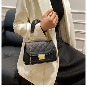 Primer plano de bolso acolchado negro con cadena dorada y asa plisada en modelo