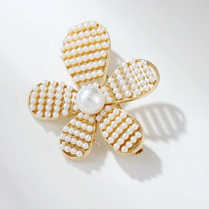 Macro shot of gold camellia brooch with intricate pearl petals and a white background