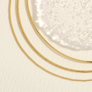Close-up of three 18K gold-plated snake chains featuring flat polished metal links