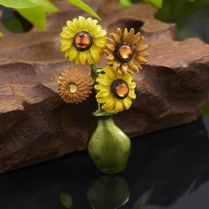 Artistic close-up of sunflower vase brooch with vibrant enamel petals on wood