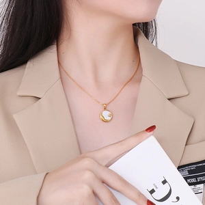 Minimalistische gouden titanium ketting met witte schelp zon en maan hanger op een model