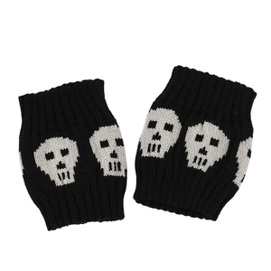 Macro detail of knit leg warmer featuring a white skull pattern on a black fabric background