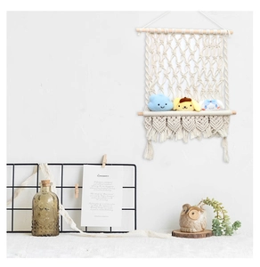 Détail d'une décoration murale bohème en corde de coton tissée avec pompons et bois