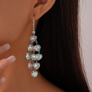 Détail d'un mannequin portant de longues boucles d'oreilles à pompons et cœurs bleus