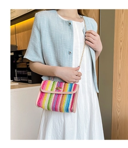 Close-up of rainbow woven bag with pink trim, gold chain strap, and twist-lock detail