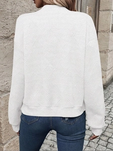 Detail of white women jacket showing the textured geometric diamond pattern on the fabric