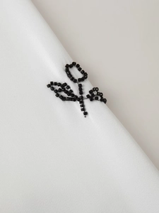 Detailed view of elegant black floral beadwork embroidery on smooth white satin fabric