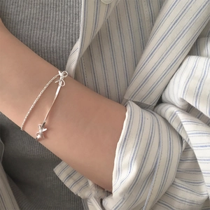 Détail du bracelet double couche en argent avec nœud papillon porté au poignet délicat