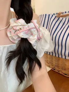 Close-up of floral scrunchie with pink rose patterns on a hairstyle with warm lighting