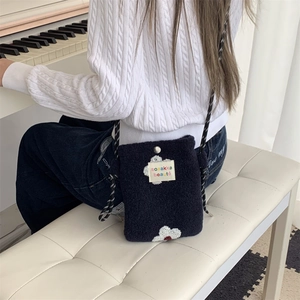 Detail view of the plush floral crossbody bag with logo patch and metal snap closure