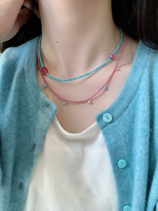 Detail of layered turquoise and pink beaded necklaces with pearls on a model