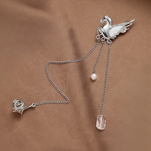 Macro detail of silver Pegasus brooch with rhinestones and elegant chain tassels