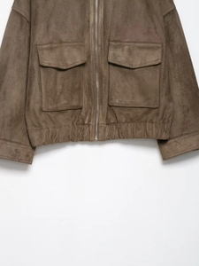 Detailed view of brown suede jacket with silver zippers and symmetrical flap pockets