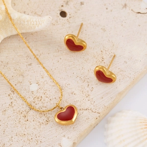 Golden heart necklace and earrings set with red inlays on a coral stone with sea shells