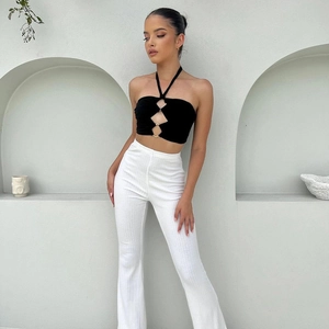 Black halter cutout crop top with white ribbed trousers on a fashion model