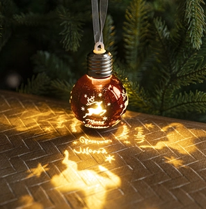 Detailed view of glowing warm orange Christmas ball projector with reindeer and star patterns