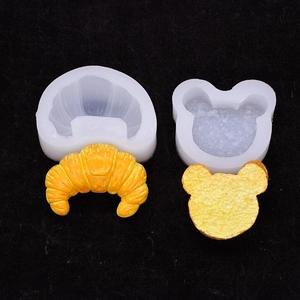 Silicone molds for croissant and bear head shaped candles or pastries on black backdrop