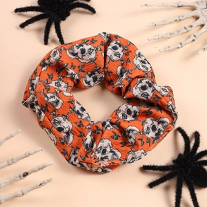 Detail of orange Halloween scrunchie with skull and bat prints on textured fabric