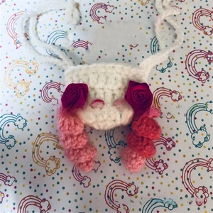 Detailed view of a handmade knitted animal nose warmer with festive red roses