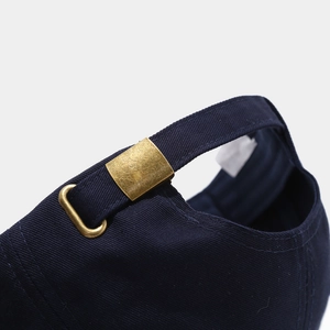 Detailed close-up of navy cotton baseball cap with vintage brass adjustable metal buckle