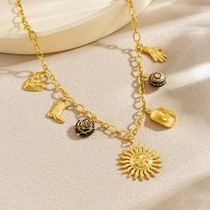 Vintage gold-plated sun and cowboy charm necklace with black enamel accents on beige surface