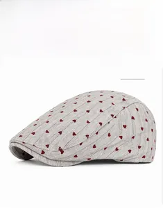 Detailed close-up of khaki flat cap with embroidered red heart on twill fabric