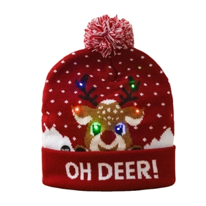 Red knitted Christmas hat with LED reindeer pattern and pompom top on white background