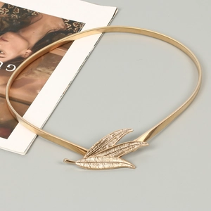 Detail of golden elastic metal belt featuring a textured triple leaf buckle for dresses
