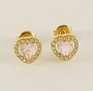 Vue macro de boucles d'oreilles cœur dorées avec gemme rose et cristaux clairs