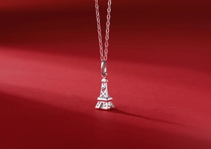 Macro view of Eiffel Tower silver pendant with sparkling moissanite on red background