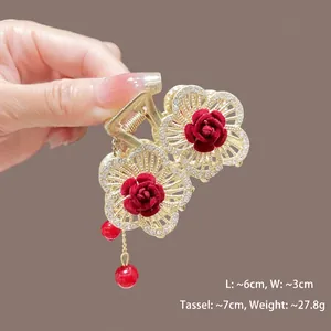 Détail d'une pince à cheveux rose rouge avec pompons dorés et strass sur cadre métallique
