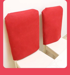 Detail of red fabric Christmas chair back covers with festive cartoon prints on white chairs