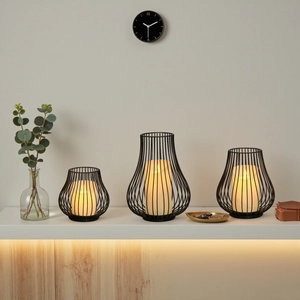 Three-piece black wire metal candle holders with warm LED candles in tiered sizes