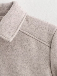 Detail of oatmeal wool blend jacket showing clean collar structure and shoulder stitching