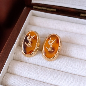 Detailed view of amber resin earrings with gold metal logo in a luxury jewelry box