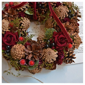 Detail of Christmas wreath with pine cones, red velvet roses and festive berries