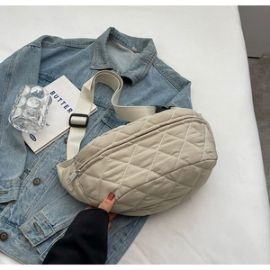 Close-up of beige quilted nylon crossbody bag with adjustable strap on denim jacket