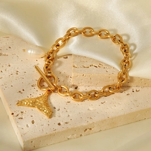 Detail von Gold-Fischschwanz-Anhänger und weißer Perle an grober Edelstahlkette