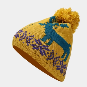 Close-up of winter knit beanie featuring yellow fabric with blue reindeer and snowflake patterns