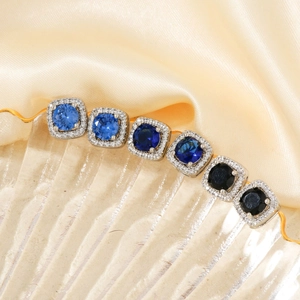 Elegant square zircon earrings with gradient blue stones on a champagne silk background