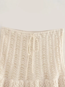 Dettaglio della maglia e coulisse in vita su minigonna in crochet crema con pizzo