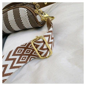 Detail of bohemian geometric woven chest bag with wide strap and gold metal hardware