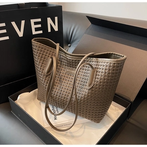 Close-up of brown woven tote bag with textured leather detail in a premium gift box