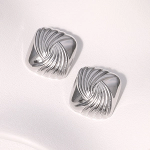 Macro shot of polished silver metal earrings with unique radial textured pattern detail