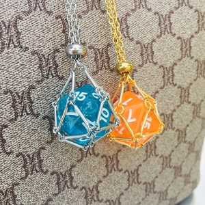 Close-up of resin polyhedral dice inside gold and silver metal cage pendants
