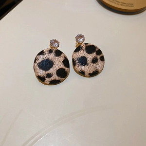 Macro detail of vintage leopard print round earrings with a sparkling zircon stone inlay